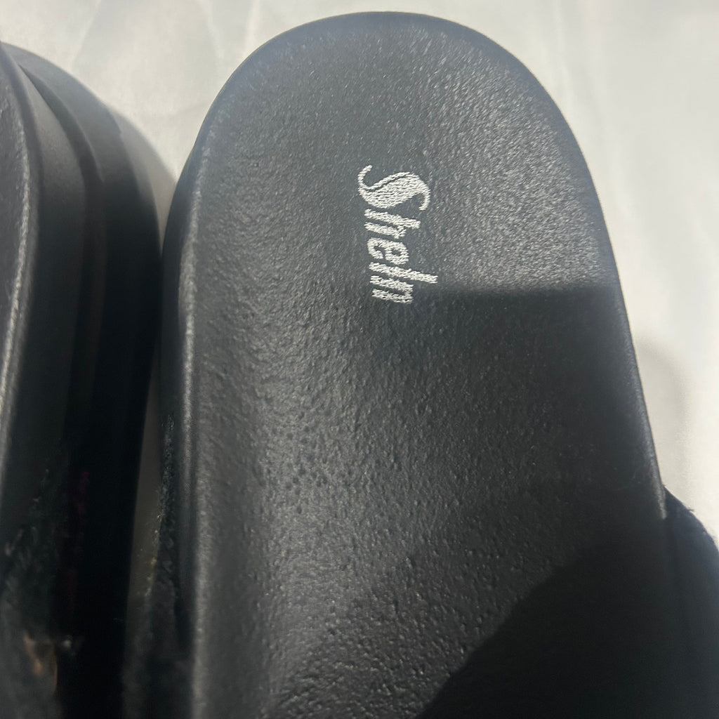 Black slide sandal with 'Sheln' branding on a white background