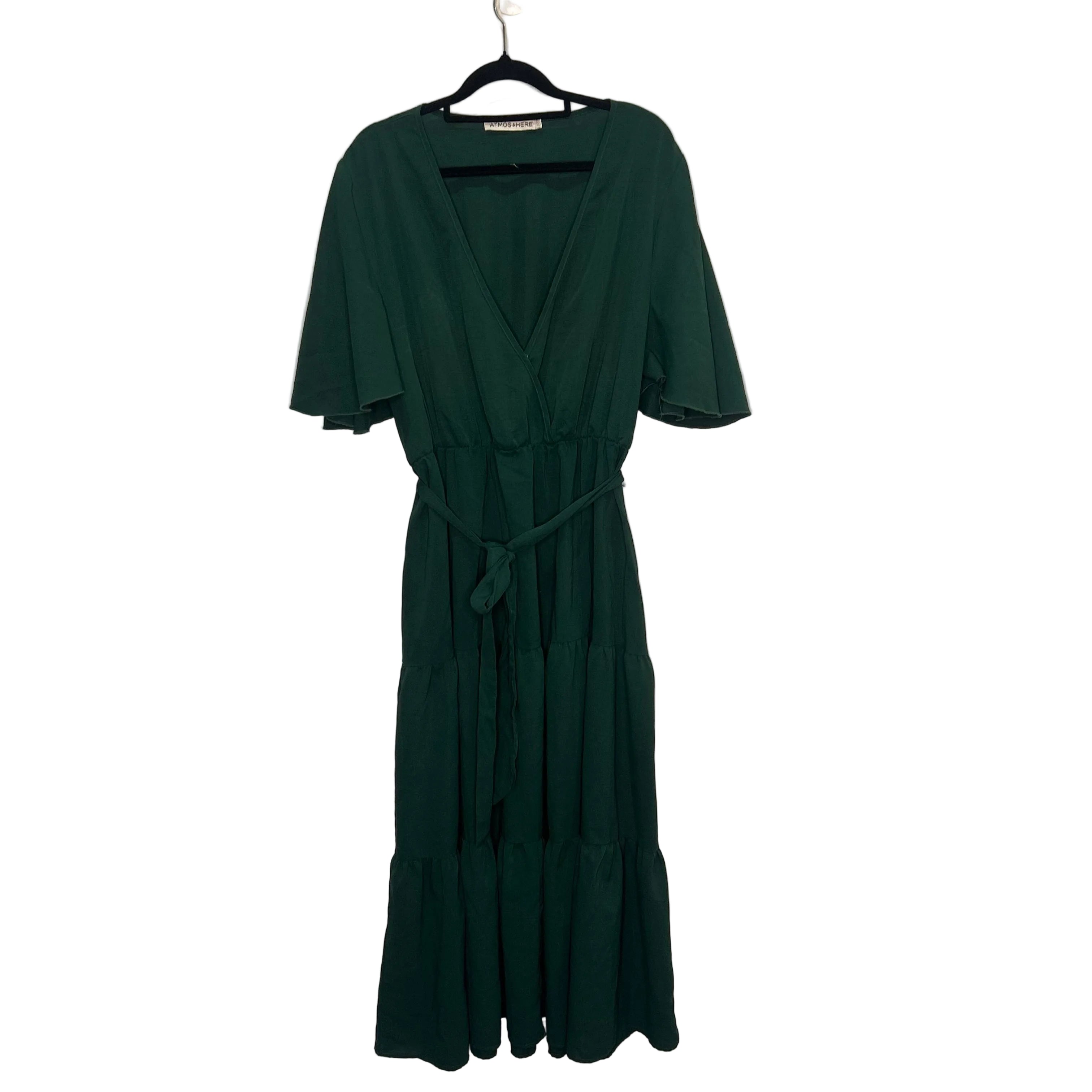 Green dress on a hanger against a plain background