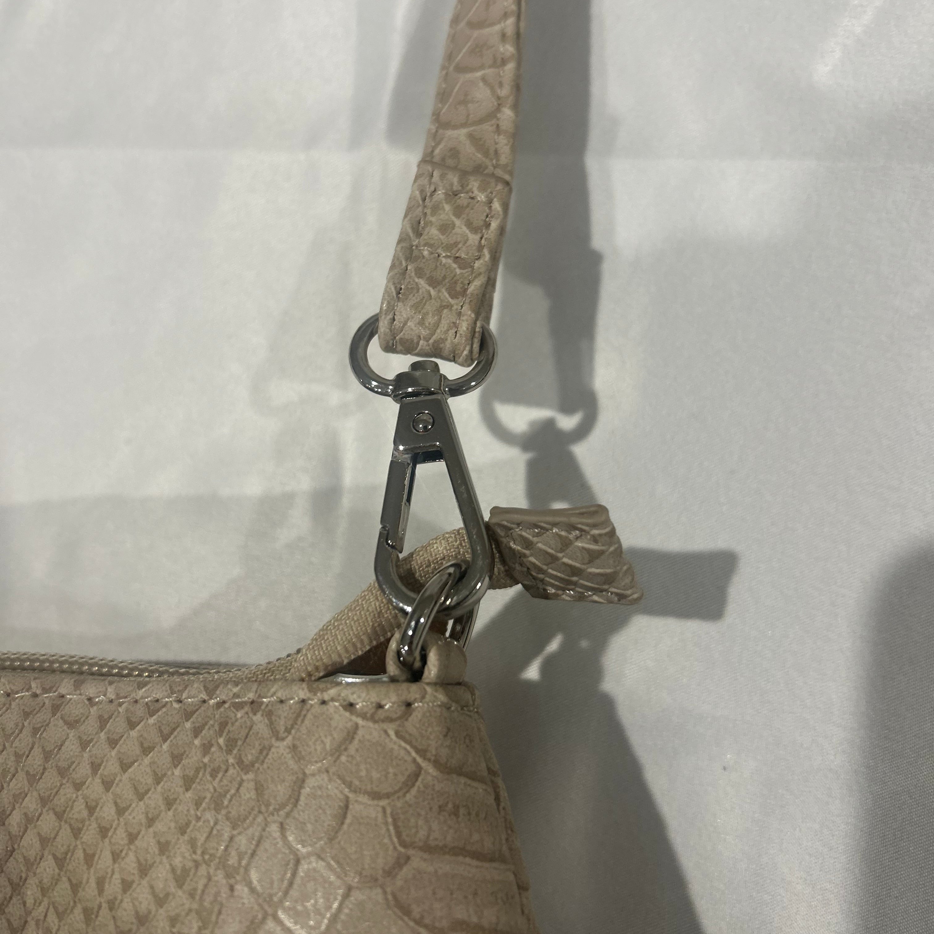 Close-up of a beige textured handbag with a strap on a white background