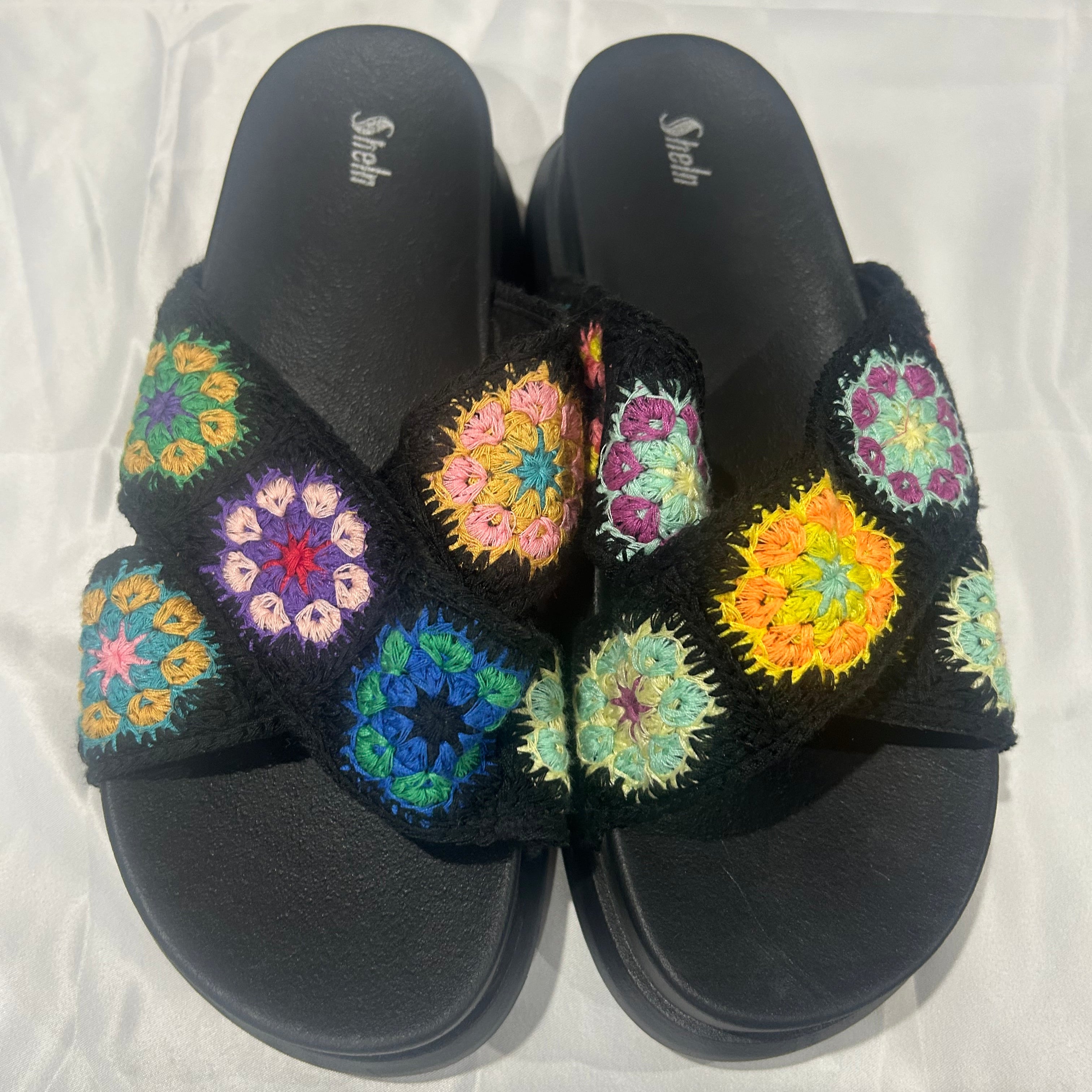 Black sandals with colorful floral patterns on a white background