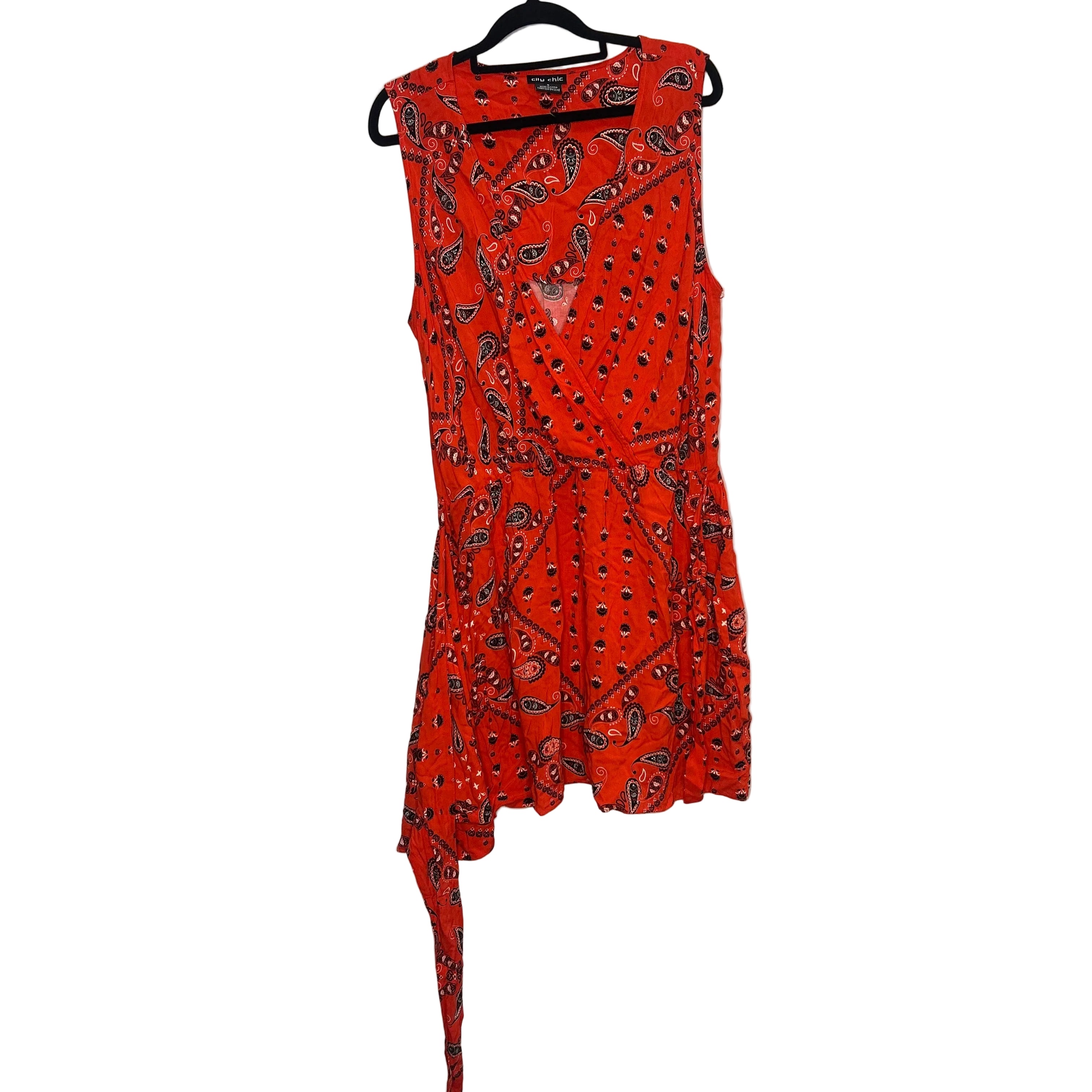 Orange dress with black pattern on a hanger against a plain background