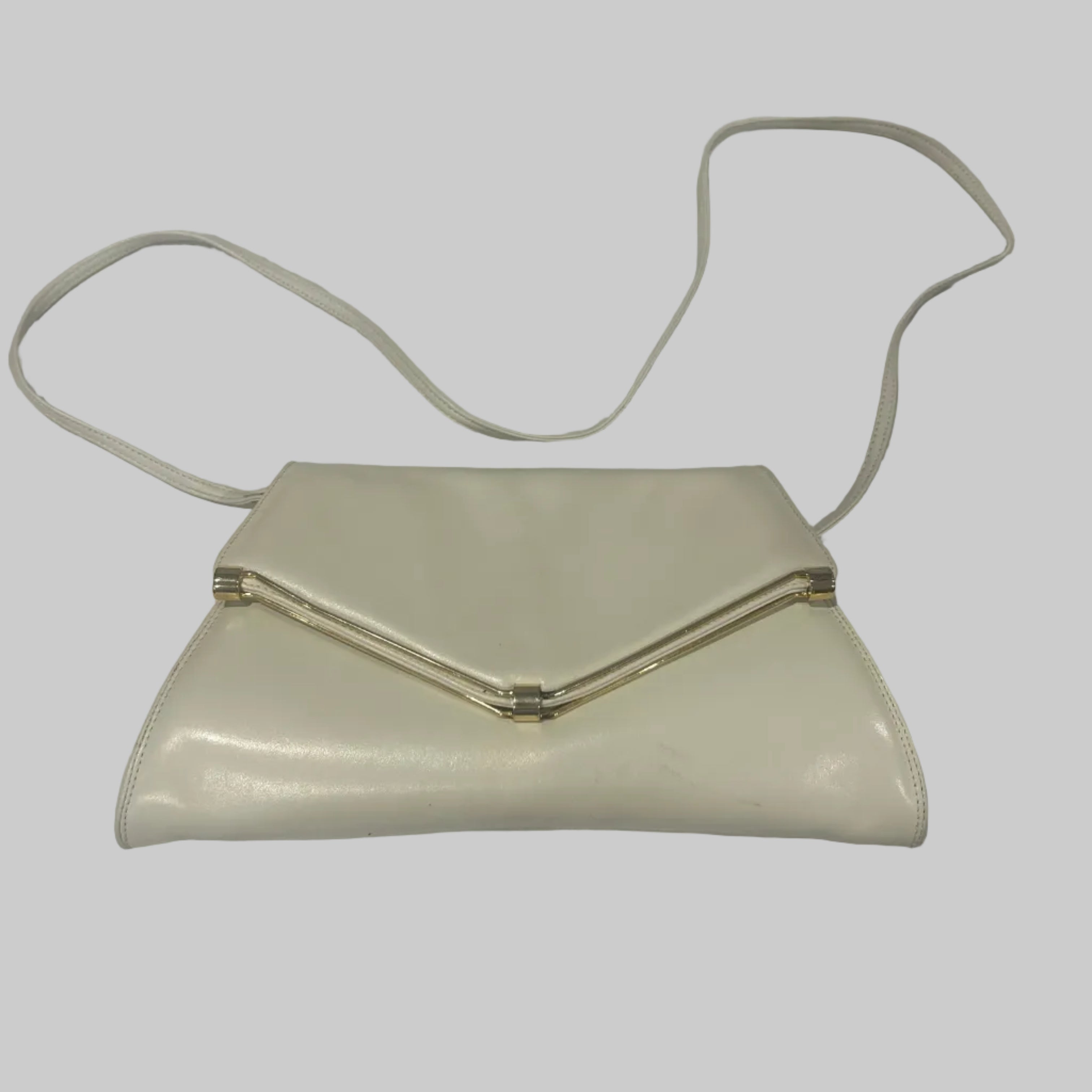 White clutch bag with a strap on a white fabric background