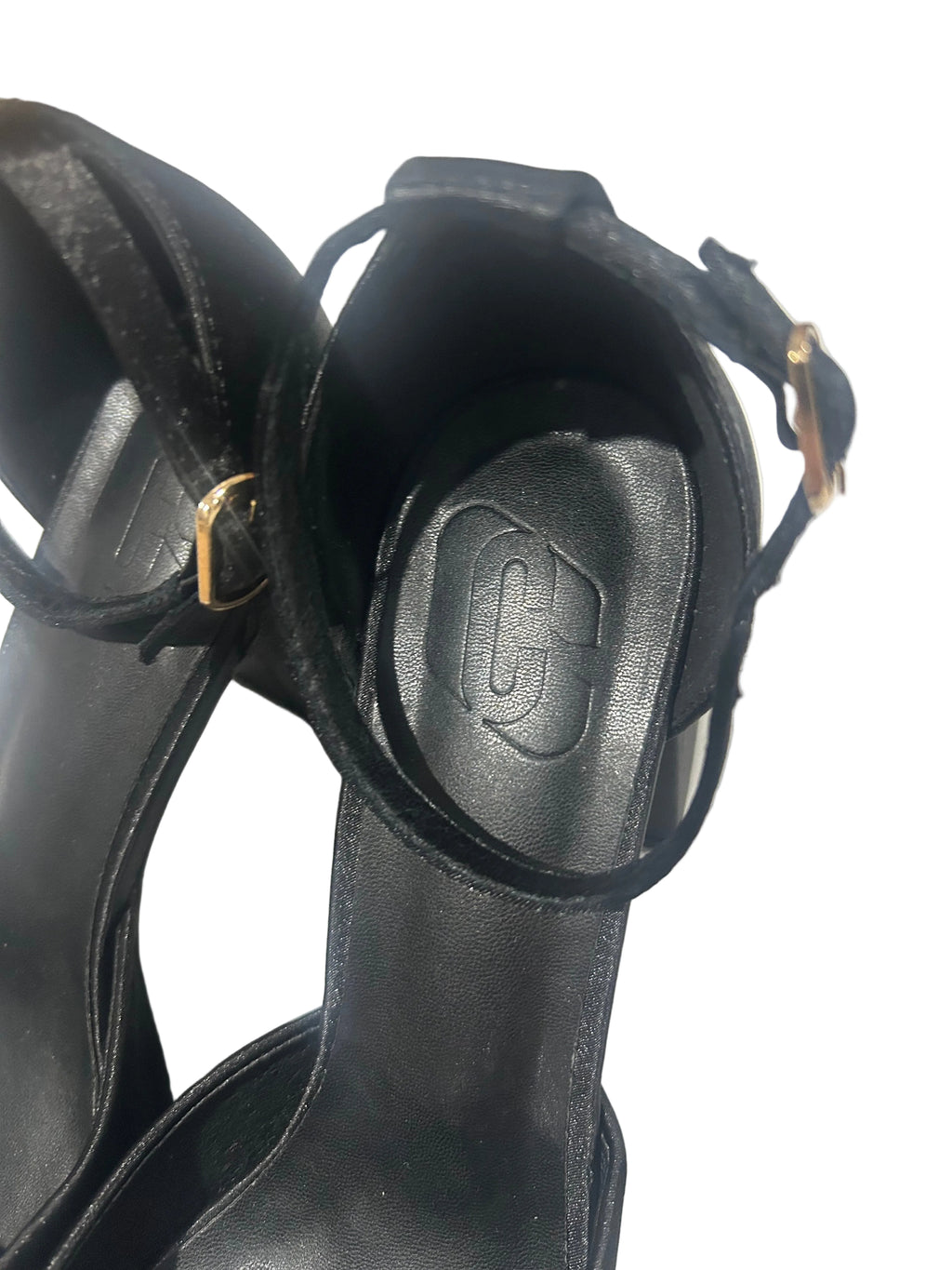Close-up of a black leather boot with a brand logo on a light gray background