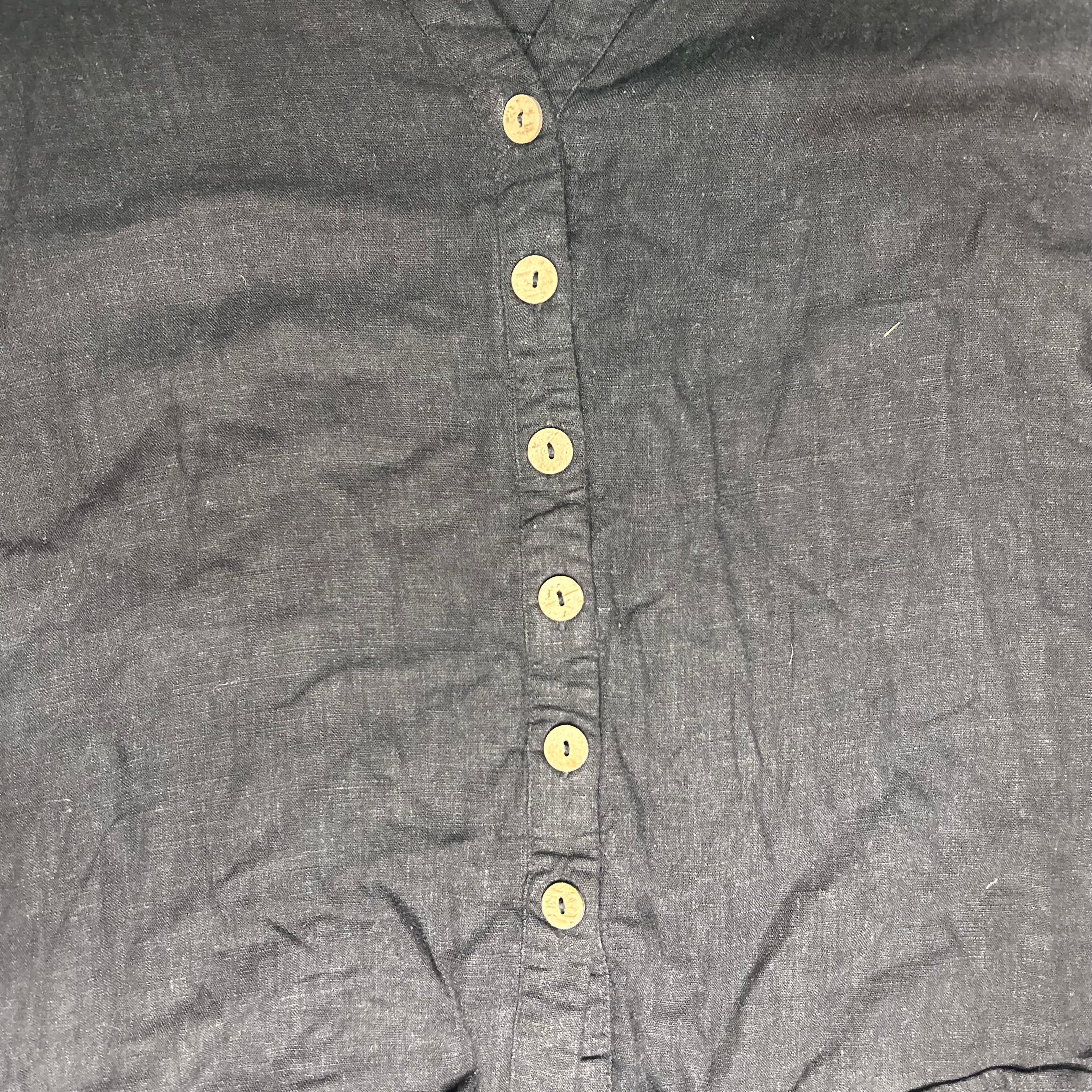 Close-up of a gray shirt with yellow buttons on a plain background