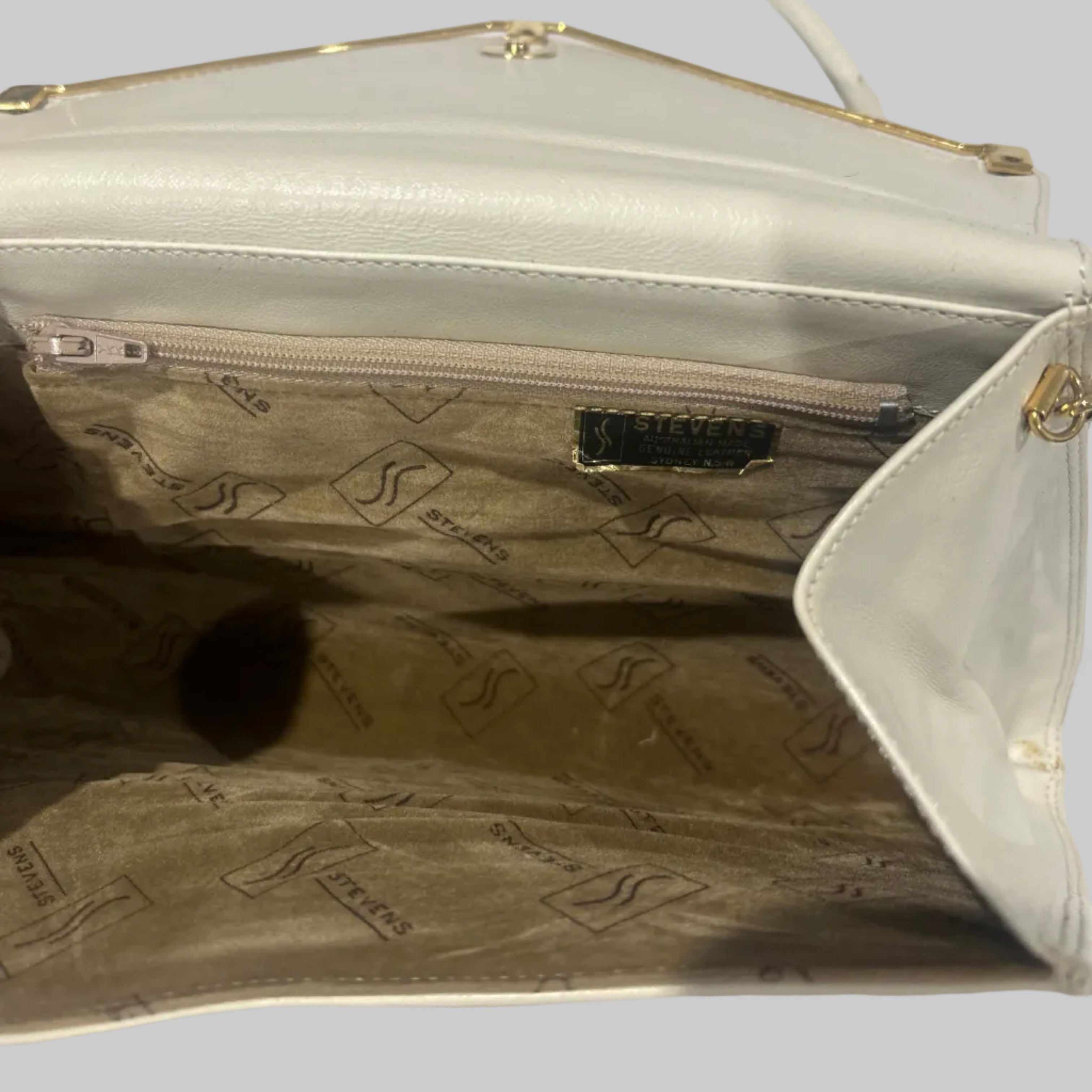 Close-up of a beige handbag with brand logo on a white background