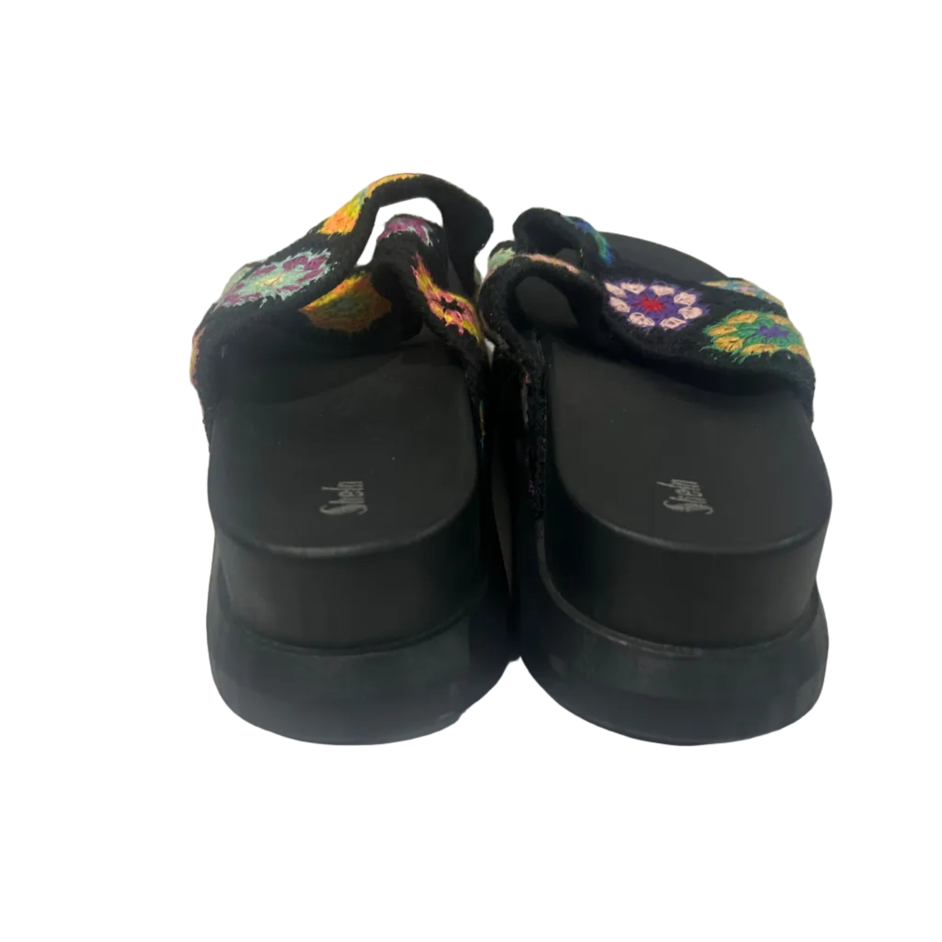 Black shoes with colorful floral patterns on a white surface