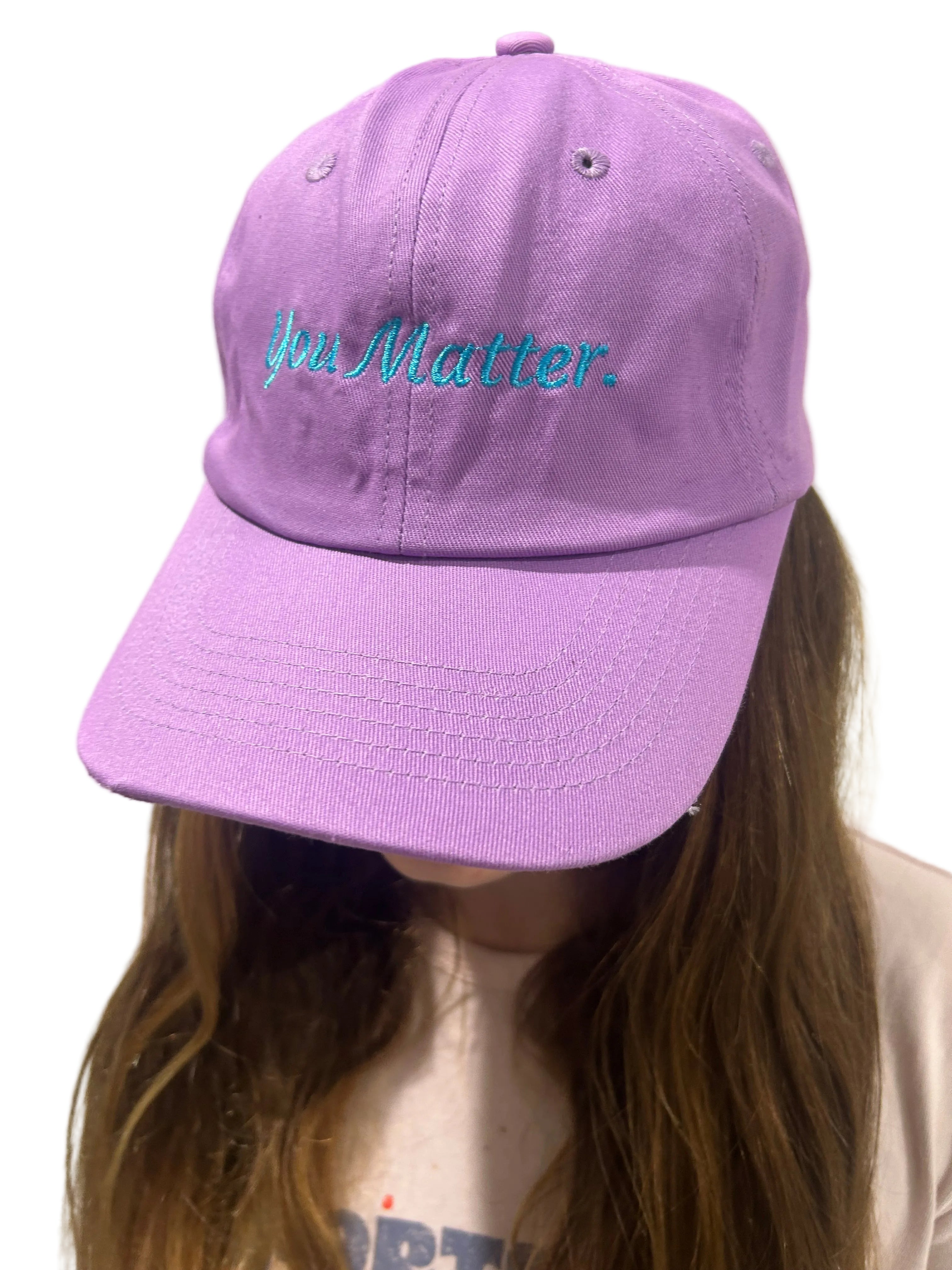 Purple cap with text worn by a person on a light background