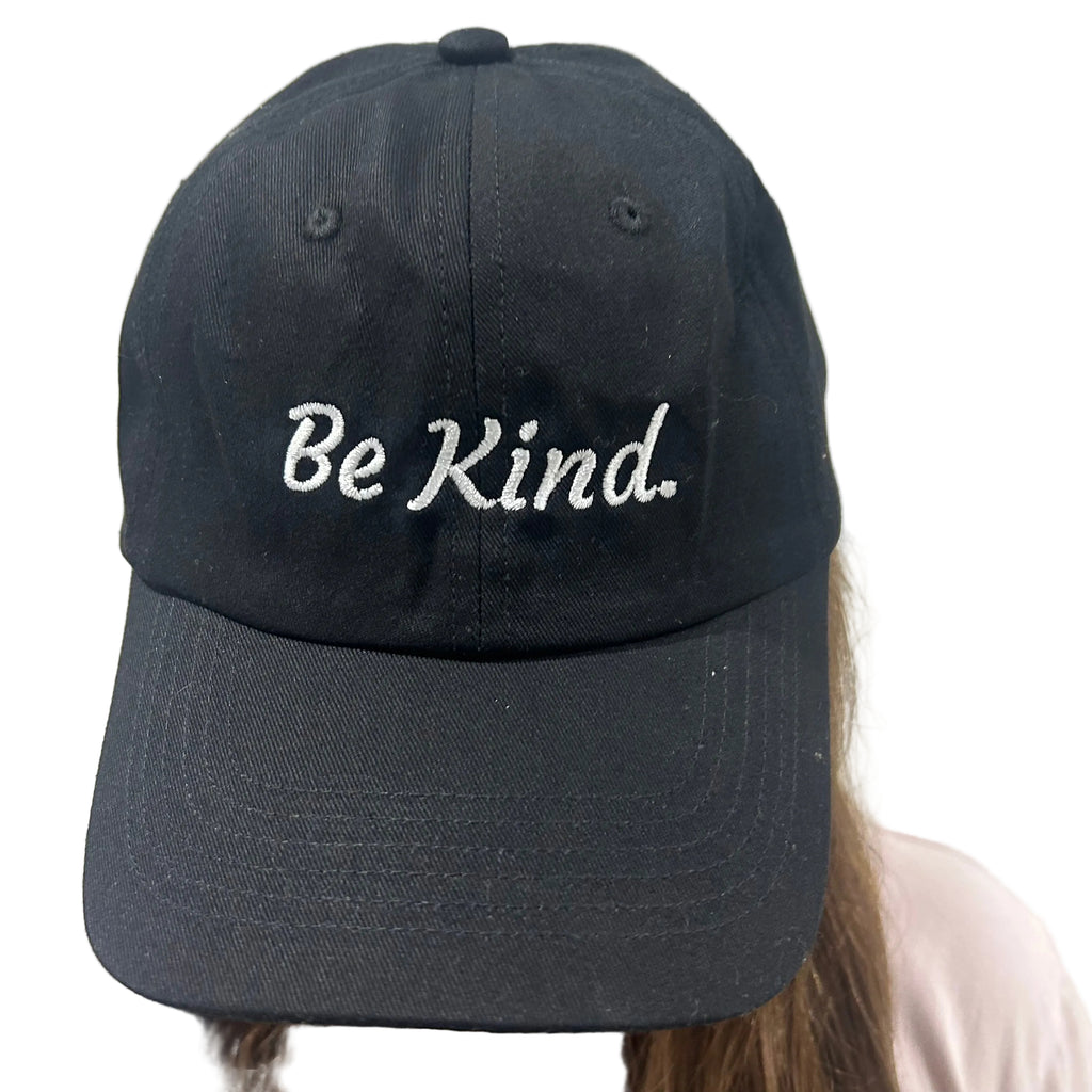 Black cap with 'Be Kind' text worn by a person against a plain background