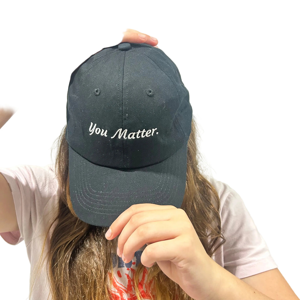 Person wearing a black cap with 'You Matter' text on a plain background