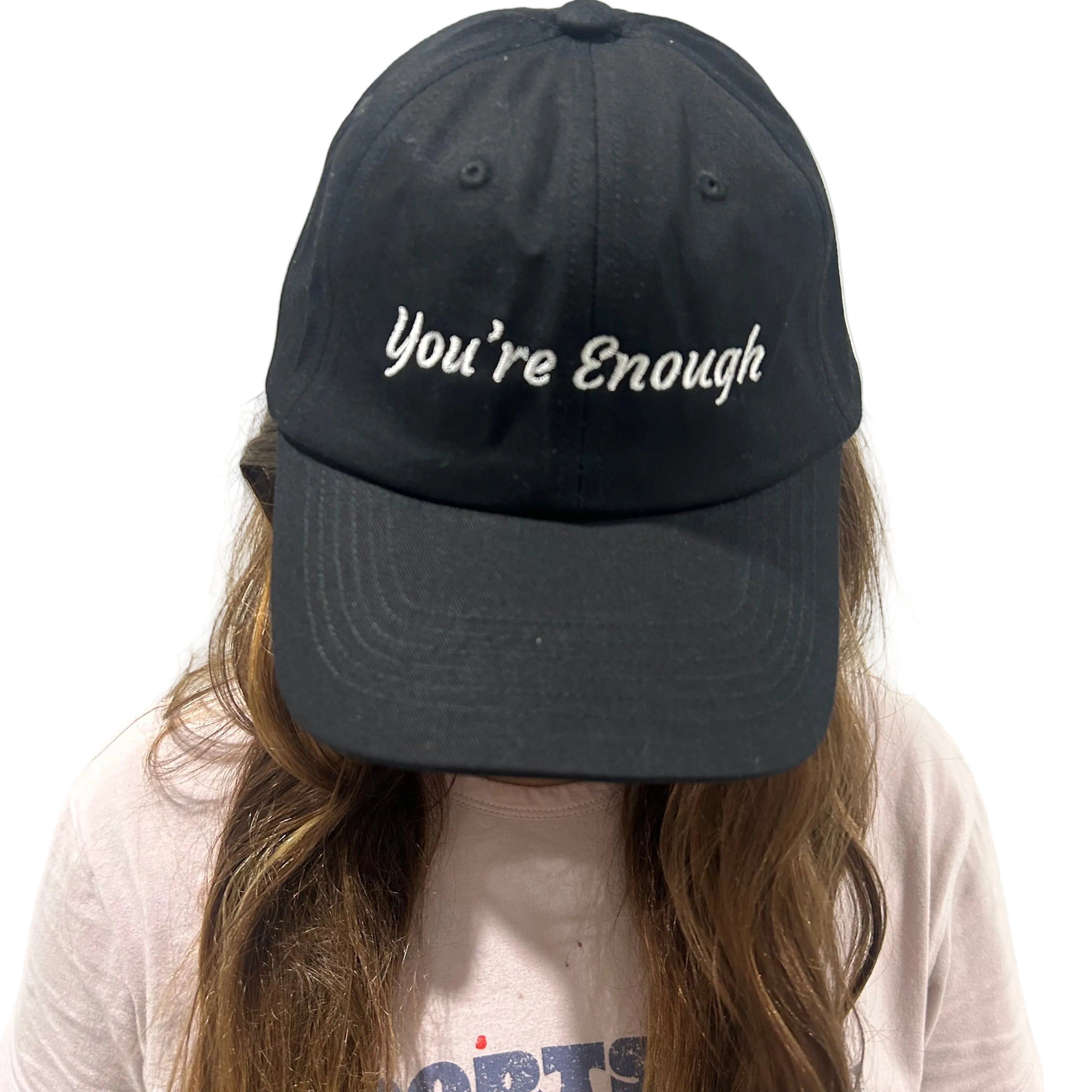 Person wearing a black cap with 'You're Enough' text on a plain background